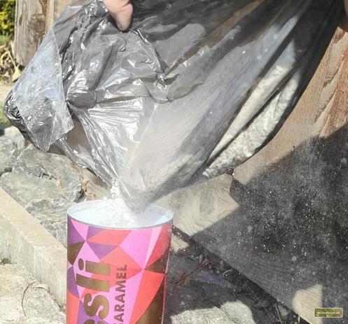 Perlit wird aus einem Beutel in eine Dose umgefüllt, wobei es ordentlich staubt, trotz dass das Material mit "2x gesiebt und somit fast staubfrei" beworben wurde.
