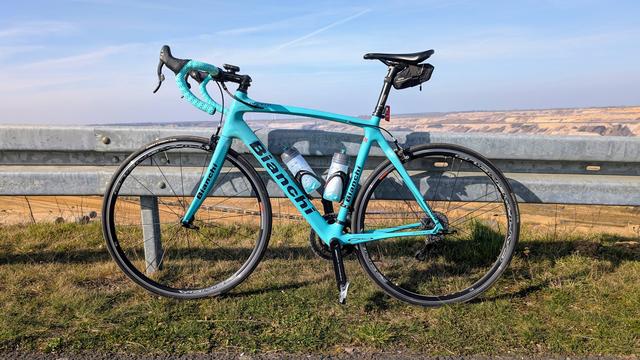 Mein Bianchi-Rennrad lehnt an einer Leitplanke unmittelbar am Rand der Tagebaugrube.