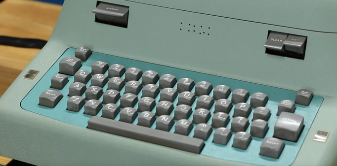 Screenshot of a green/teal colored electronic typewriter with the number row starting with '2' since you can use 'l' for one.