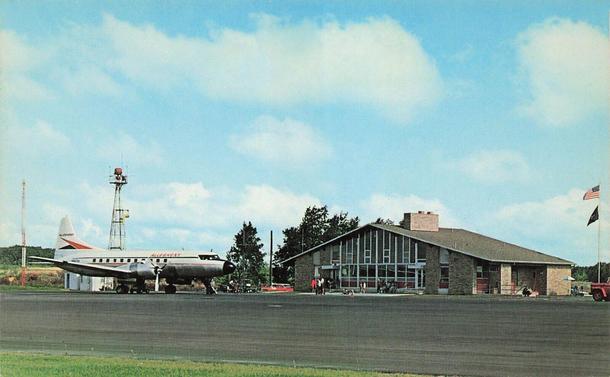 Plane is parked on the left, and the terminal is on the left. It is a slanted roof structure