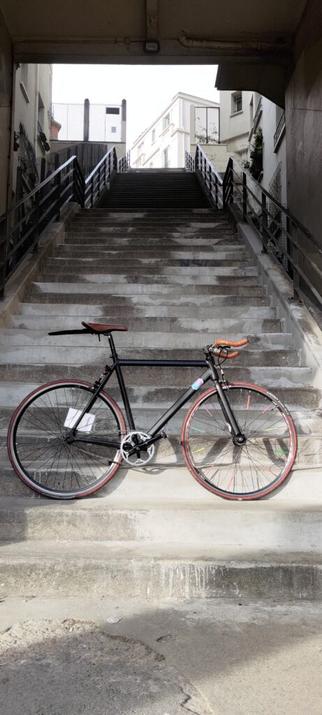 Un vélo type single posé au pied d'une longue volée de marches qui montent