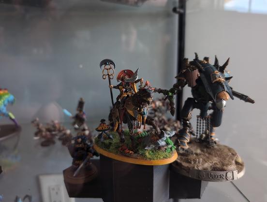 Collection of miniatures from Games Workshop in a glass display case sitting on a ranking podium.