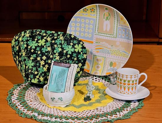 Tea tableau in the colors of fresh baby vegetables, with a shamrock- patterned tea cozy and vintage china including Belleek Irish china and a tiny green leprechaun and clover, resting on vintage crocheted doilies in green, white, and yellow.