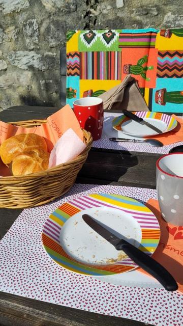 Buntes Geschirr, bunte Sitzkissen, ein Korb mit Brötchen, im Sonnenlicht