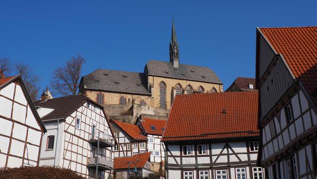 Fachwerkhäuser, oberhalb die ehemalige Klosterkirche, darüber klarer blauer Himmel