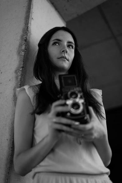 Untersichtiges Portrait eines Mädchens, das eine TLR Kamera in der Hand hält und in die Ferne schaut