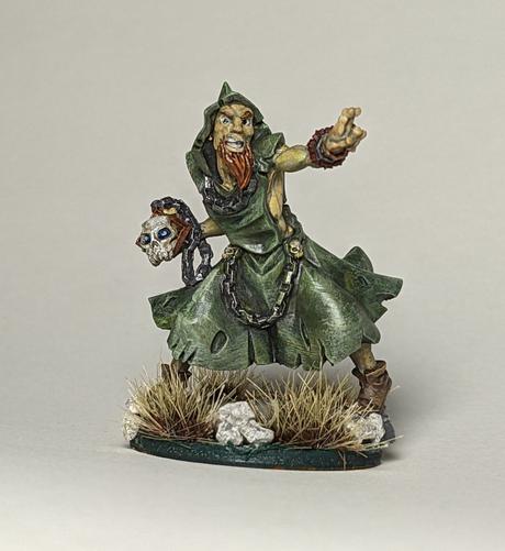 A forest druid well versed in weed. Green robes, silver chains, red beard, and skull in hand, this spellcaster is busy casting spells. He has a cool skull in his hand and looks wild like a pagan.