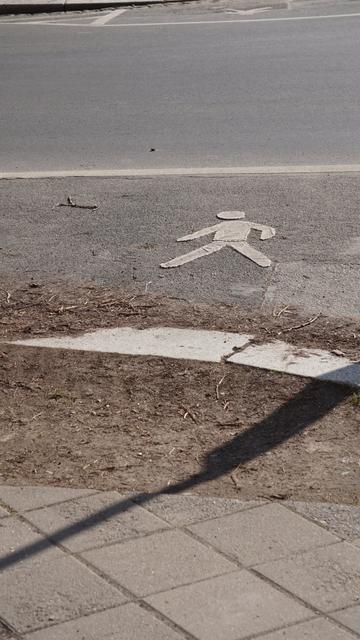 eine innerstädtische Kreuzung

Es ist an der Krümmung eine Stelle markiert, an der Fußgänger gnädigerweiße Queren dürfen

dafür ist ein laufendes Männlein auf dem Asphalt aufgebracht

die Bordsteinkannte ist ebenerdig und von Kurve-schneidenden PKW/LKW endgültig flach gedrückt (obwohl die Fahrbahnrand-Markierung nochmal 1m weiter innen läge)

zwischen Bordstein und Fußweg ist ein halber Meter unbefestigter Boden

nach Wetter also entweder Schlamm oder Staub
