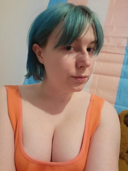 Revy with her blue hair tied back behind her ears.
She has no makeup
She's wearing a orange singlet
And the borbs be borbin