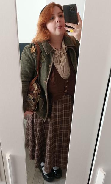 Outfit check en el espejo: camisa con cuello de bebé beige con un lazo, chaleco marrón oscuro, falda marrón a cuadros, chaqueta verde de lana con hojas, bolso tapizado de ositos, calcetines blancos y Mary Janes negras (todas las fotos son iguales pero con una pose distinta)