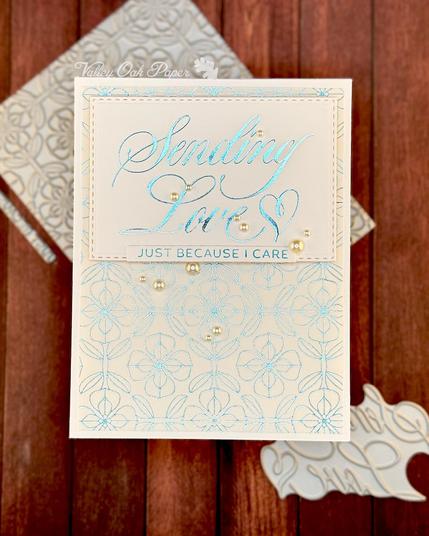 White greeting card with a very large greeting in an elegant, script font. The greeting reads "Sending Love. Just because I care." The background is a stylized flower pattern.