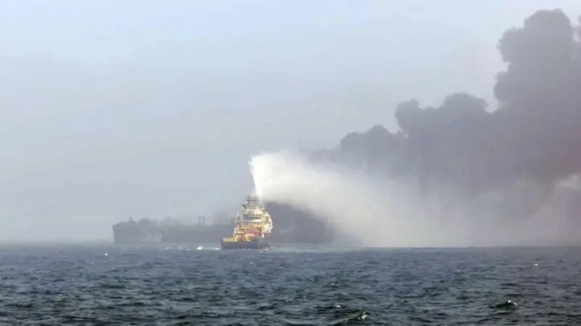 Image shows a large fire that is spread across the North Sea and thick black smoke billowing upwards. A rescue vessel appears to be spraying the blaze with water.