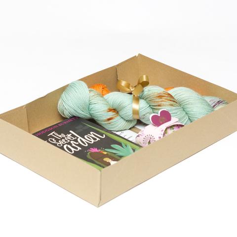Picture shows an open A4 box containing yarn, a book and other items which are obscured by the sides of the box.