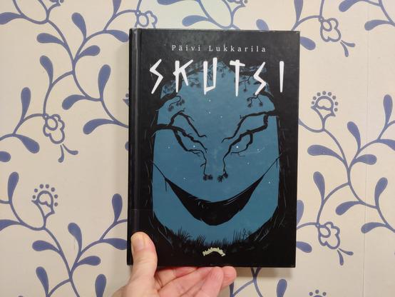 Päivi Lukkarila: Skutsi (kansikuva seinää vasten/ book in hand against a wall)