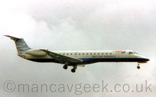 Side view of a white, twin engined jet airliner flying from left to right at a low altitude, with undercarriage lowered and flaps extended from the rear of the wings, suggesting it is about to land.
The plane has a dark blue belly, with black "British Airways" on the lower forward fuselage, below a twisted red and blue ribbon.
The tail has wavy light blue, dark blue, red, and white  stripes.
Cloudy grey sky fills the rest of the frame.
