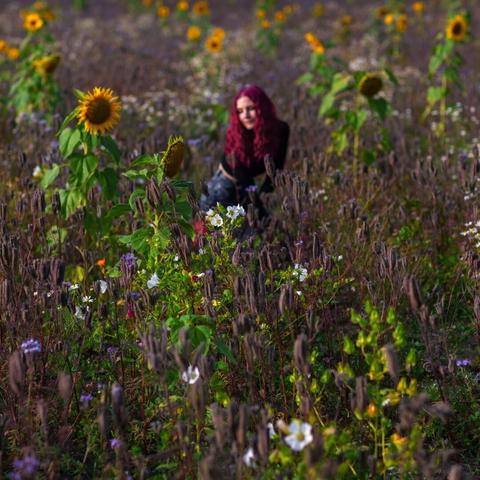 A red haired woman enjoying sunshine in the middle of a field of flowers