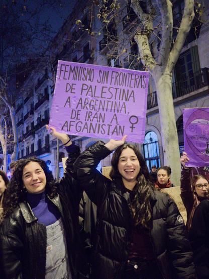 Two girls holds up a sign written in Spanish that reads "FEMINISMO SIN FRONTERAS, DE PALESTINA A ARGENTINA, DE IRÁN A AFGANISTÁN" (Feminism without borders, from Palestine to Argentina, from Iran to Afghanistan), with a symbol of female gender.

Dues noies sostenen un cartell escrit en castellà que diu "FEMINISMO SIN FRONTERAS, DE PALESTINA A ARGENTINA, DE IRÁN A AFGANISTÁN" (Feminisme sense fronteres, de Palestina a l'Argentina, de l'Iran a l'Afganistan), amb un símbol de gènere femení.