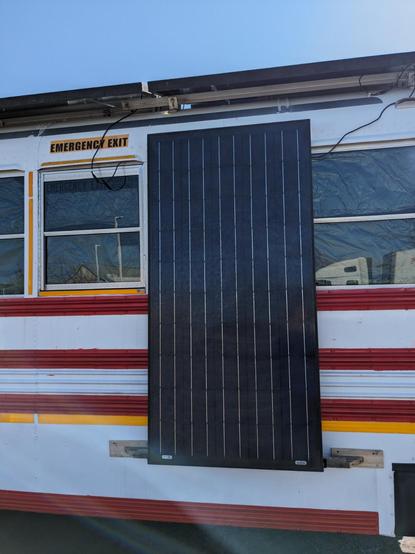A solar panel fastened to the side of the Vulpibus on a clear sunny day. More solar panels are on the roof.