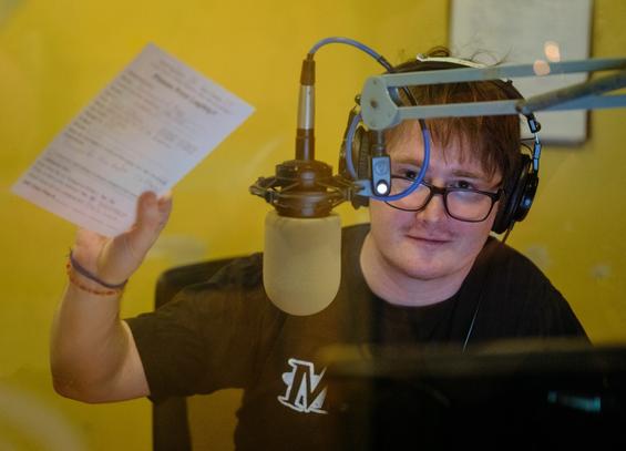 A man near a microphone holds up a white sheet of paper.
