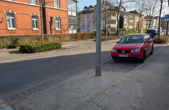 Vor einer Laterne sieht man eine frisch gepflasterte Fläche. Rechts neben der Laterne parkt ein PKW gegen die Fahrtrichtung.