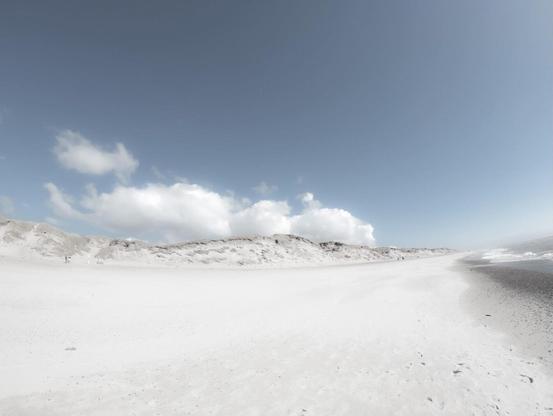 Ein heller Sandstrand zieht sich weit entlang der dänischen Küste, während weiße Dünen und weiche Wolken eine beruhigende, fast surreale Atmosphäre schaffen. Der klare Himmel und die offene Weite verleihen der Szenerie ein Gefühl von grenzenloser Freiheit.