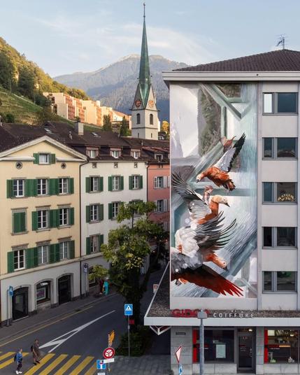 L1B3R0 – Chur, Switzerland:
A vertical mural by Vesod featuring several birds dynamically flying through geometric structures. Painted realistically with a strong sense of motion, the mural blends wildlife and abstract forms seamlessly against the backdrop of Chur, Switzerland.