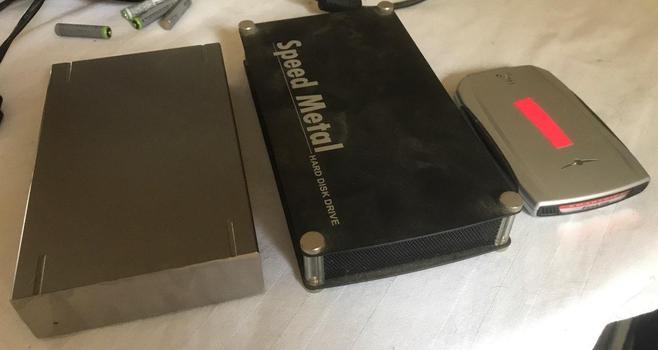 Three external hard drives, on a white cloth surface.
