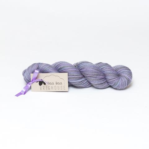 Picture shows a skein of yarn in shades of purple, lilac, black and grey.