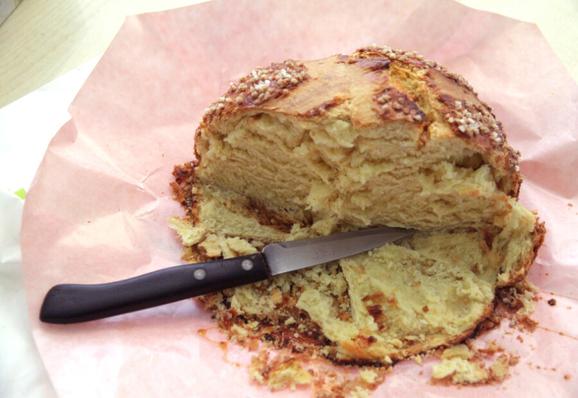 Photo d’une mouna entamée à moitié, avec le couteau qui a servi à couper les parts. La mouna est une brioche en forme de dôme, d’origine algérienne, qui se consomme traditionnellement durant les fêtes de Pâques.