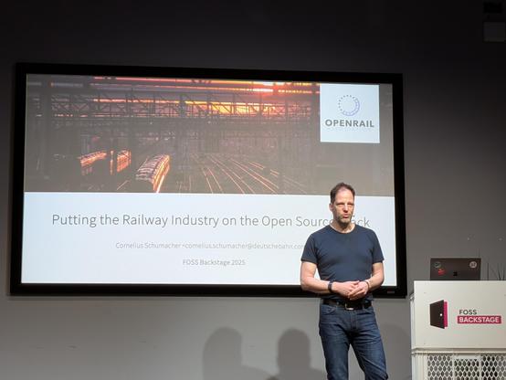 Photo of Cornelius on the stage with the title slide in the background
