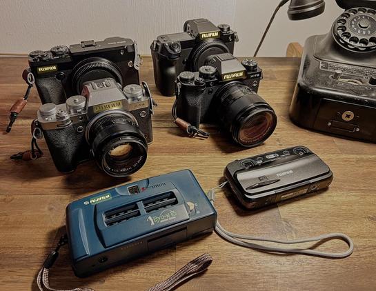 6 Fujifilm-Kameras. Hintere Reihe: GFX50R, GFX100S. Mittlere Reihe: X-T4, X-T5. Vordere Reihe: Rensha Cardia Byu-16, Real 3D W3