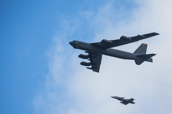 A B-52 Stratofortress flying over central Stockholm, escorted by a Swedish Jas39 Gripen fighter jet.