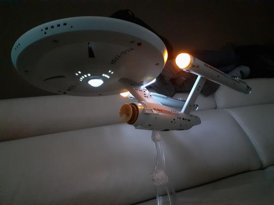 Die Enterprise schräg von vorne unten im leicht dunklen mit ihrer Beleuchtung fotografiert.