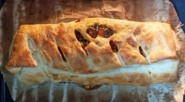 Der fertige braun gebackene Strudel auf dem Blech. Durch die Einschnitte sieht man etwas die Füllung