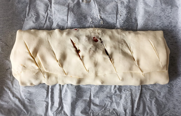 Der fertig gerollte und 6 mal eingeschnittene Strudel vor dem Backen auf dem Blech.