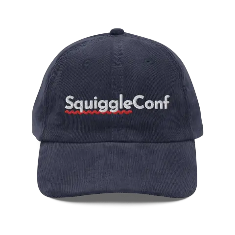 Navy Corduroy Cap
“A navy-blue corduroy baseball cap embroidered with the word ‘SquiggleConf’ in white, featuring a wavy red line underneath.”