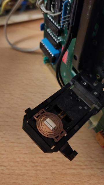 A black plastic rectangular part with a read/write head on a flex pcb stuck in place where it should be.