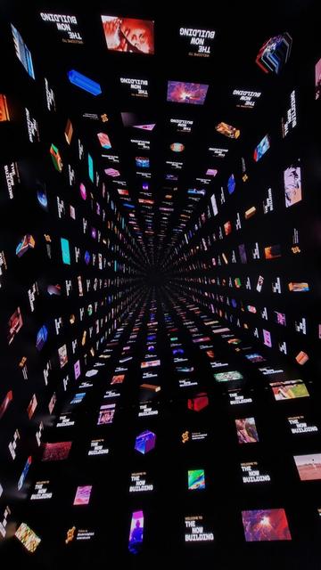 Photo of the ceiling screen with immersive art of the Outernet in London, UK. This art piece show a various icons endlessly going upwards creating a tunnel.