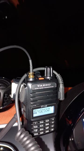 Yaesu FT-4X handheld in front of a car dashboard, against a black sky. The frequency displayed is 432.550MHz.