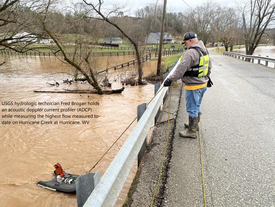 photo - USGS hydrologic technician Fred Brogan holds an acoustic doppler current profiler (ADCP) while measuring the highest flow measured to-date on Hurricane Creek at Hurricane, WV.