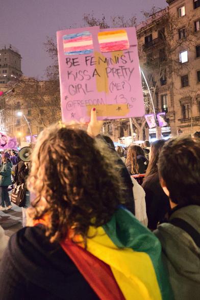 Girl with rainbow flag holding up a sign with trans flag and lesbian flag and text "Be feminist, kiss a pretty girl (me?). @freedom_1.3"

Noia amb bandera de l'arc de Sant Martí sosté un cartell amb la bandera trans i la bandera lèsbica i el text "Be feminist, kiss a pretty girl (me?). @freedom_1.3" (Sigues feminista, besa una noia bonica (mi?). @freedom_1.3)