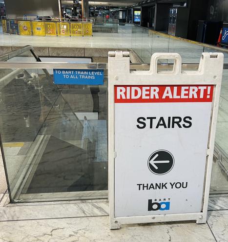 A sign in the SF BART train station, next to some stairs. A big red bar at the top says "RIDER ALERT!" The urgent thing is "STAIRS". Next is an arrow pointing left, to the stairs 2 feet away. Below that, it says "THANK YOU"