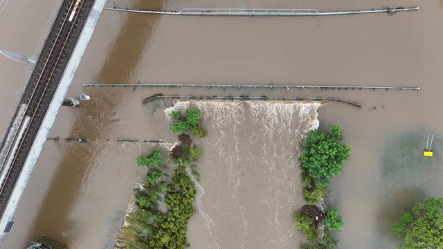Kedron brook from above. The rain has cleared, and the brook has burst its banks, completely covering a bridge, now only visible from debris caught on the handrails
