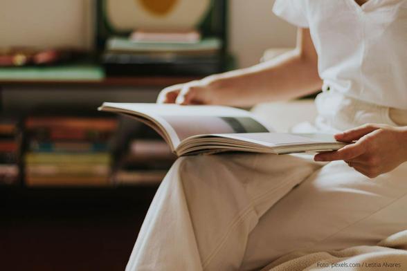 Lesende Person mit aufgeschlagenem Buch vor sich