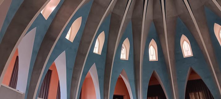Detailfoto einer Rotunde mit verschiedenen Spitzbogen-Öffnungen in mehreren Etagen. In Blau-, Grau- und Orangetönen