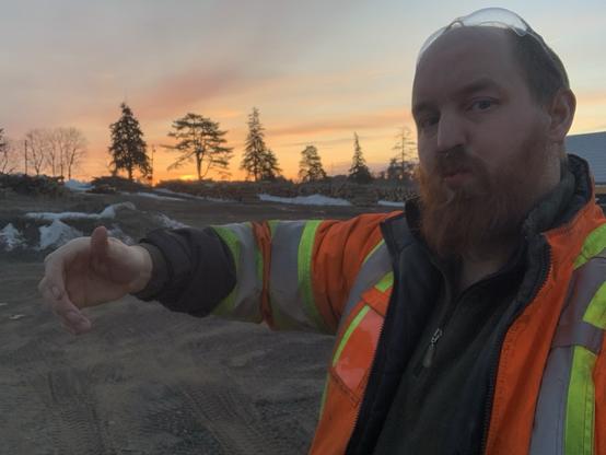 A large COs white male offers a hug. He has a large red beard and has a reflective jacket on his