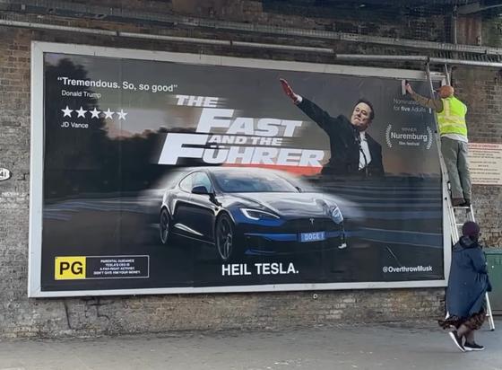 Elon Musk mit seinem umstrittenen Gruß vor einem Film Plakat: the Fast and the Führer