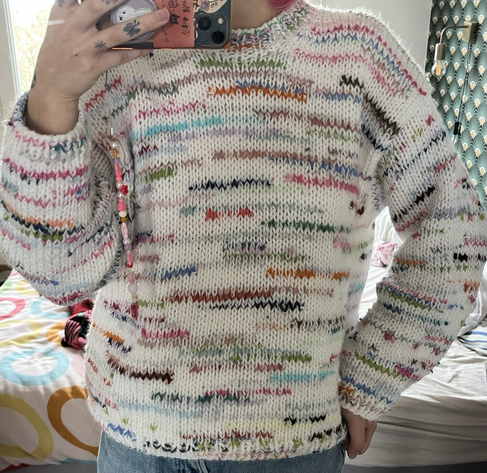 un pull blanc entrecoupé de lignes de couleur et longueur variées