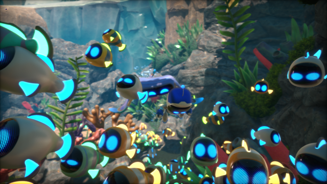 Several robots are underwater. Most of them are fish robots with a cute emoji face, and in the middle there's a little humanoid robot (the astro bot!). All of them are shining white with blue accents. They're all swimming together towards the camera