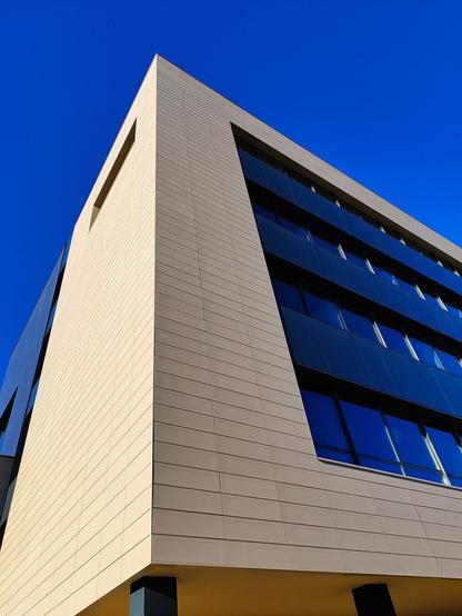 Edifici CIETD de l'UJI. La façana combina superfícies llises de color beix amb finestres fosques que reflecteixen el cel blau intens.